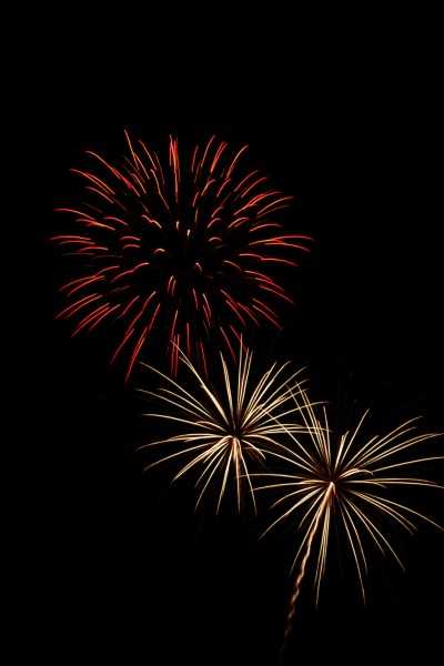 three bursts of fireworks - red orange, gold